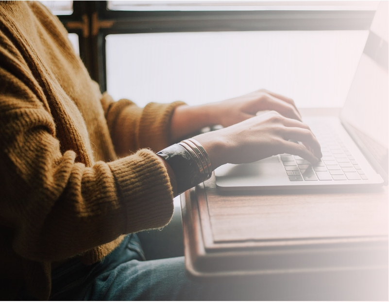 黄色いニットのパソコンを操作している人